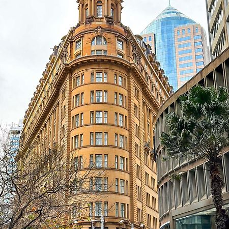 Radisson Blu Plaza Hotel ซิดนีย์ ภายนอก รูปภาพ The photo shows a distinctive architectural building with a rounded facade, featuring a tan-colored exterior and multiple windows. This building is likely situated in an urban environment, surrounded by modern skyscrapers, indicated by the glass and 