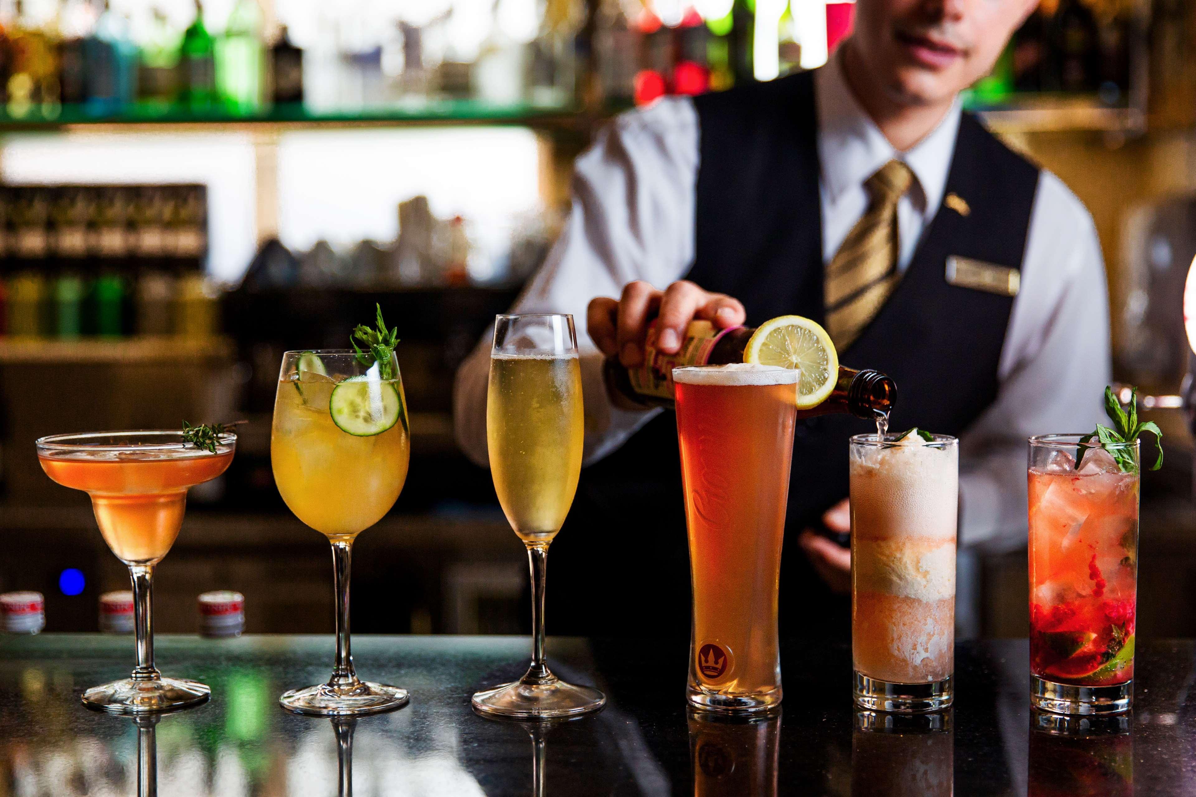 Radisson Blu Plaza Hotel ซิดนีย์ ภายนอก รูปภาพ The photo showcases a variety of colorful cocktails displayed on a bar countertop. There are six drinks in total, ranging from a vibrant orange cocktail garnished with a citrus slice to a tall glass filled with a light-colored beverage, possibly iced