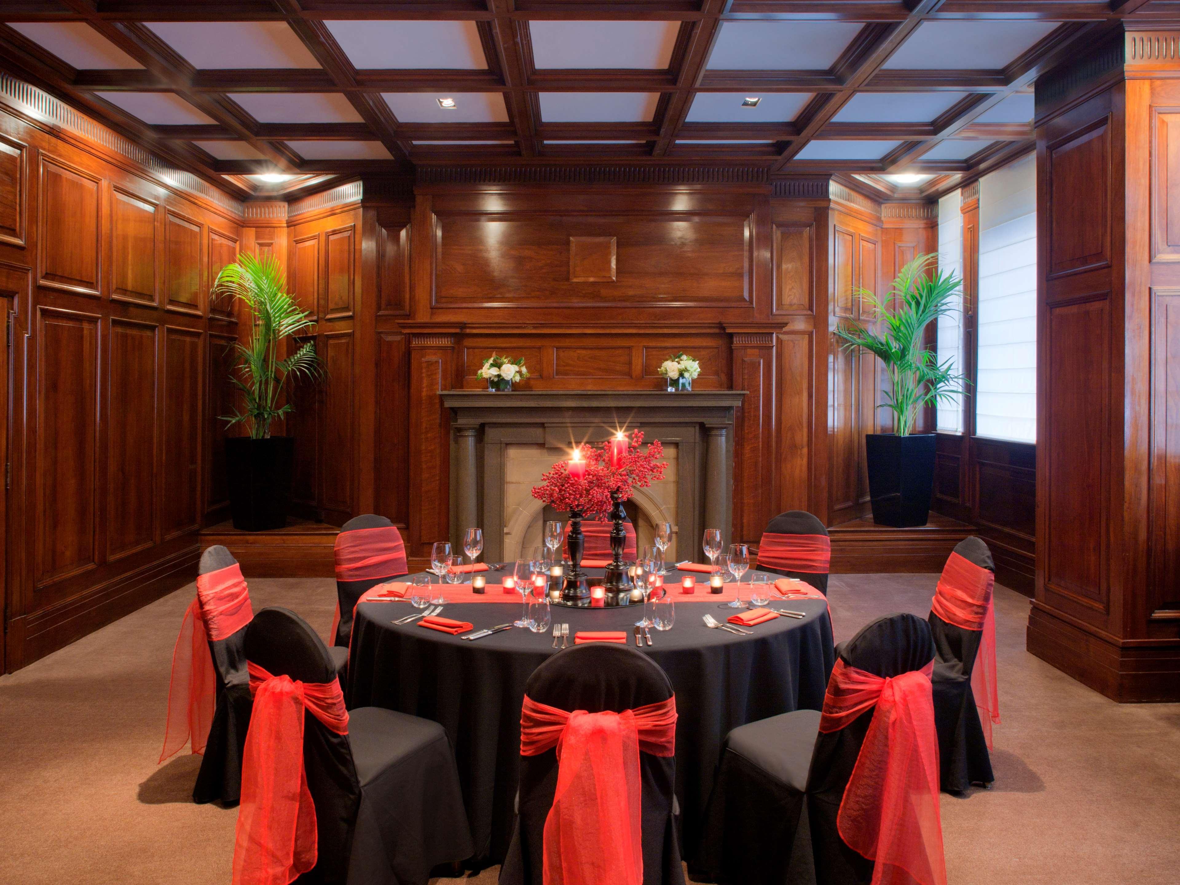 Radisson Blu Plaza Hotel ซิดนีย์ ภายนอก รูปภาพ The photo shows an elegant dining setup in a richly decorated room. The walls are made of dark wood paneling, contributing to a warm and sophisticated atmosphere. In the center, there is a round table covered with a black tablecloth, surrounded by ch