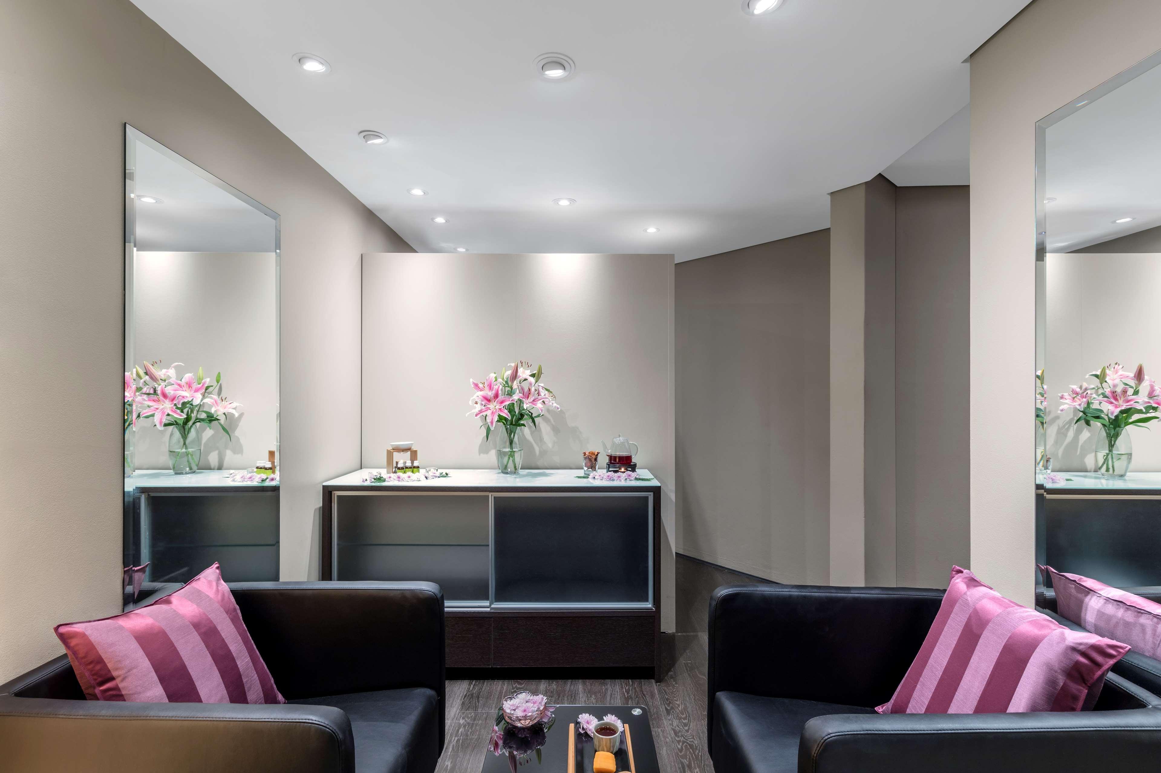 Radisson Blu Plaza Hotel ซิดนีย์ ภายนอก รูปภาพ The photo shows a modern and stylish interior, likely a waiting area or lounge. There are two black sofas with pink and white striped cushions facing each other, creating a cozy seating arrangement. In the background, a sleek cabinet or console table