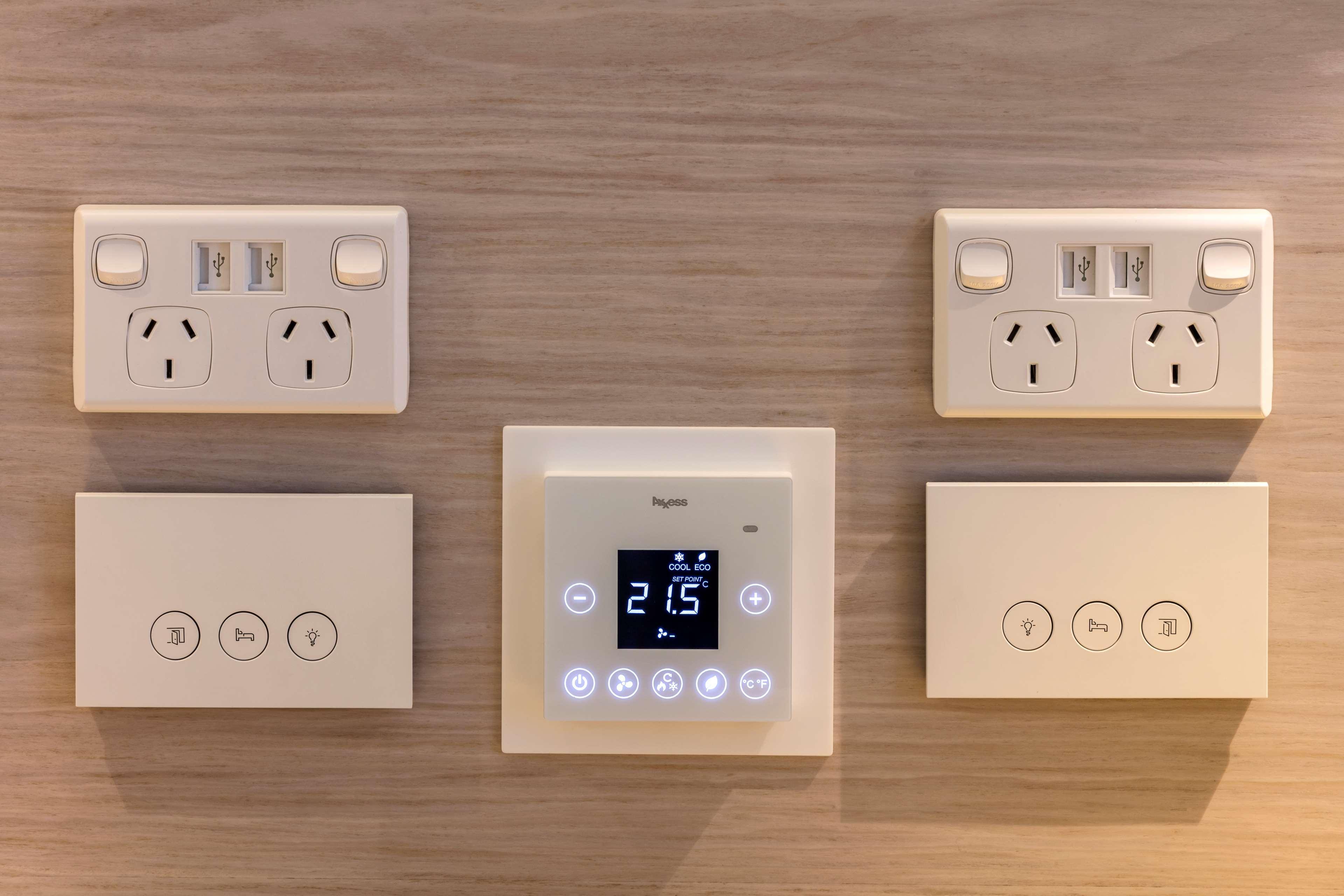 Radisson Blu Plaza Hotel ซิดนีย์ ภายนอก รูปภาพ The image shows a wall with several electrical outlets and control panels. 

- On the left and right sides, there are standard electrical outlets with two sockets each, designed for plugging in various devices.
- In the center, there is a control pan
