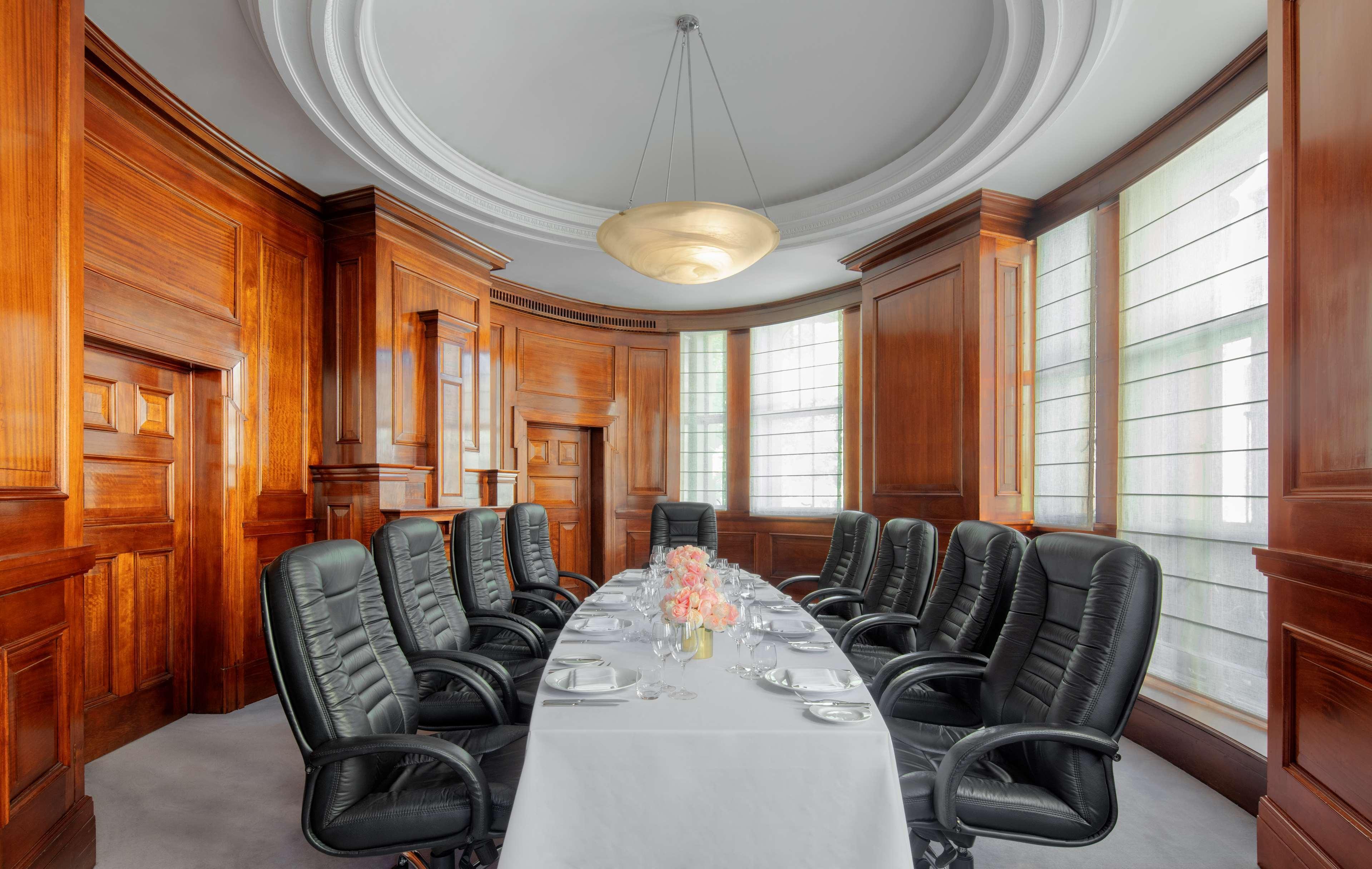 Radisson Blu Plaza Hotel ซิดนีย์ ภายนอก รูปภาพ The photo depicts a stylish conference room featuring a long, oval table set with elegant tableware. There are several black leather executive chairs arranged around the table. The room has rich wooden paneling, giving it a classic and sophisticated 